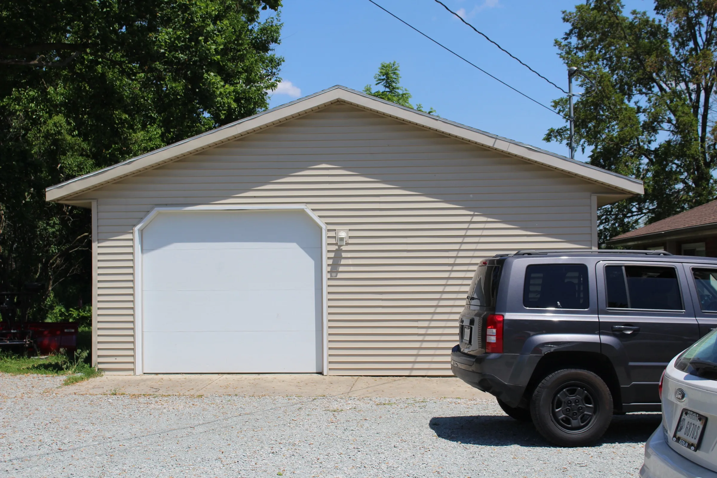 Front of the finished garage at Suite B with a white overhead door and tan vinyl siding