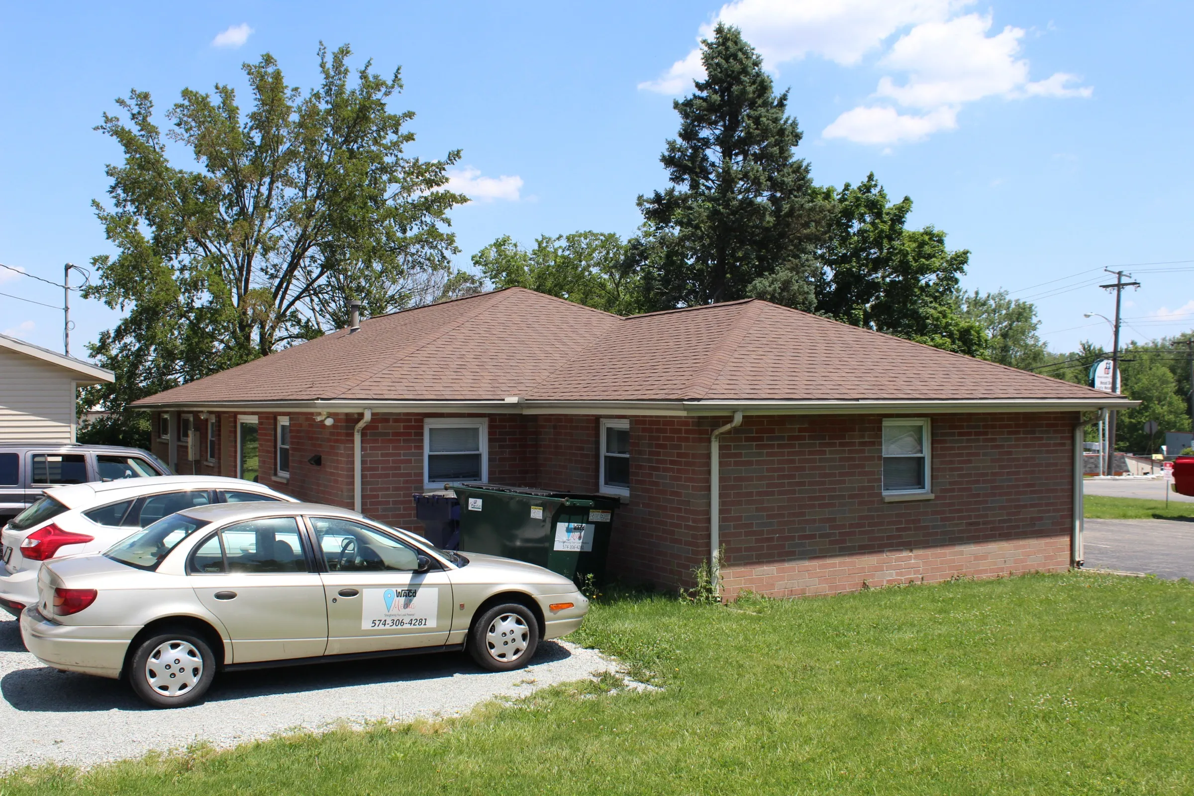 Rear corner of the brick building at 810 South Buffalo Street with a gravel parking area beside it